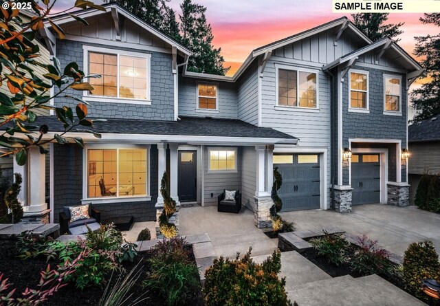 craftsman-style home with board and batten siding, concrete driveway, an attached garage, a shingled roof, and stone siding