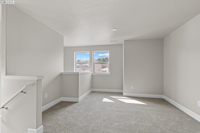spare room featuring carpet flooring, a textured ceiling, baseboards, and visible vents