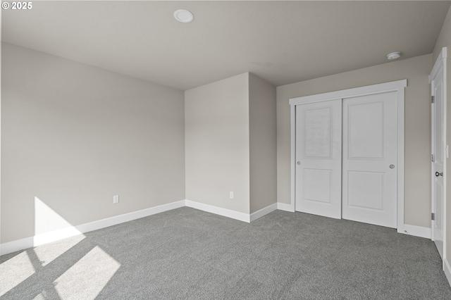 unfurnished bedroom with baseboards, a closet, and dark carpet