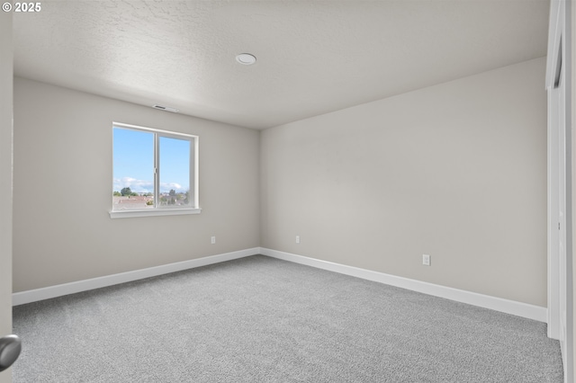 carpeted empty room featuring a textured ceiling, baseboards, and visible vents