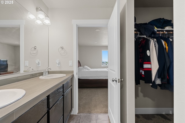 full bath featuring double vanity, a sink, a walk in closet, and ensuite bath