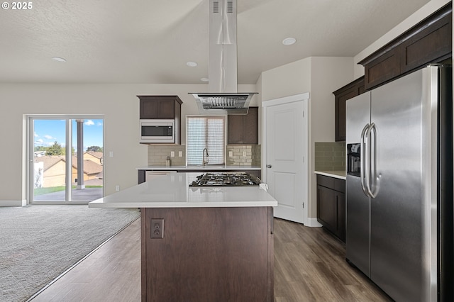 kitchen with island exhaust hood, light countertops, appliances with stainless steel finishes, and dark brown cabinets