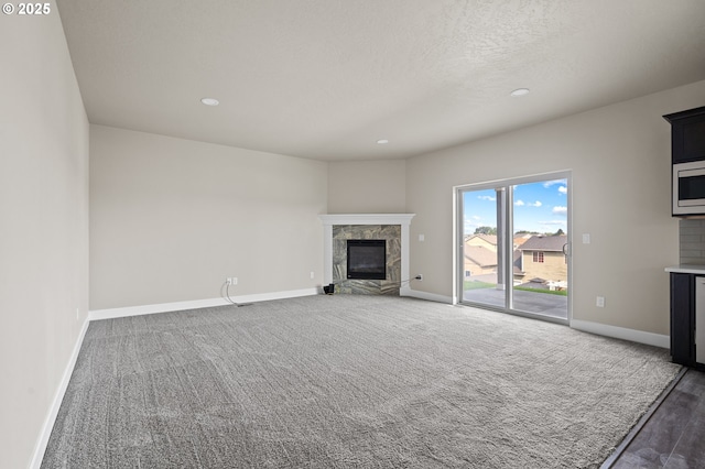 unfurnished living room featuring a textured ceiling, a fireplace, baseboards, carpet flooring, and recessed lighting