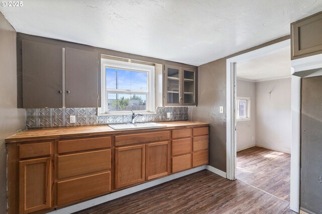 173 N Seneca Rd, Eugene, OR 97402 - kitchen with butcher block counters, dark wood-style flooring, brown cabinetry, glass insert cabinets, and tasteful backsplash