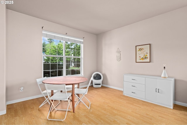 dining space featuring light wood-type flooring and baseboards