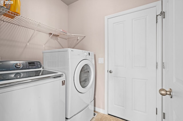 laundry room with washing machine and clothes dryer and baseboards