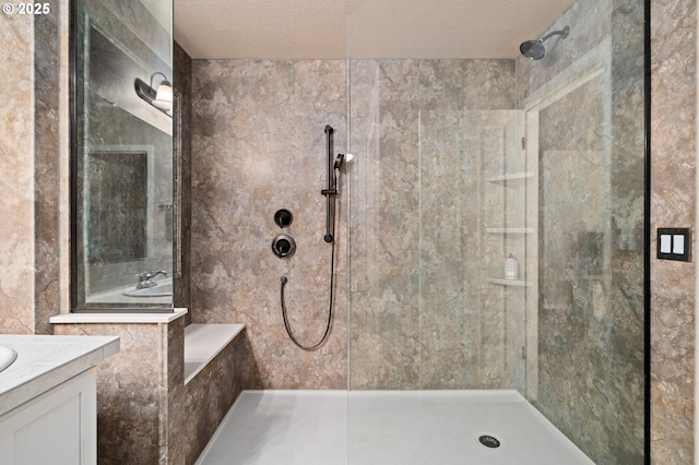 bathroom with tiled shower, vanity, and a textured ceiling
