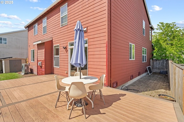 wooden deck featuring a storage shed, outdoor dining area, fence, and an outbuilding