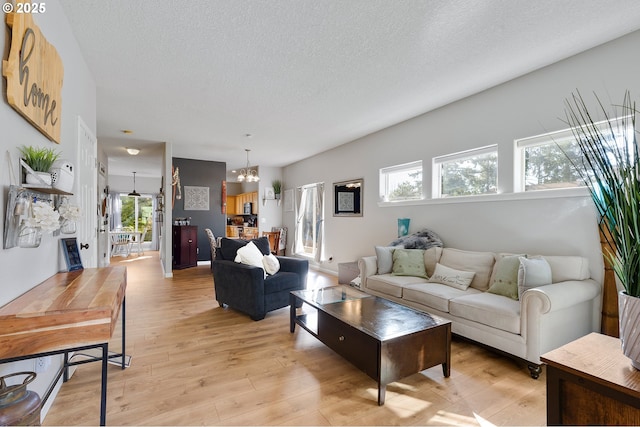 living area featuring a textured ceiling, light wood-style floors, and a chandelier