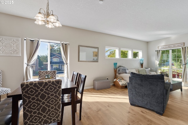 dining space featuring a notable chandelier, a textured ceiling, and light wood-style floors