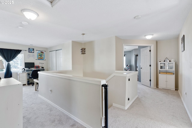 corridor featuring baseboards, an upstairs landing, light colored carpet, and a textured ceiling