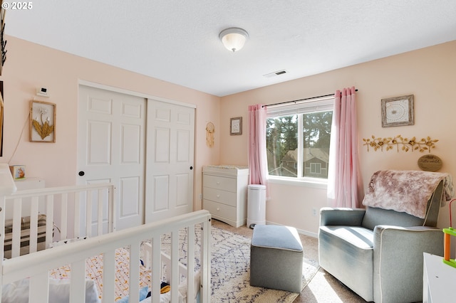 bedroom featuring visible vents, a textured ceiling, a closet, carpet flooring, and baseboards