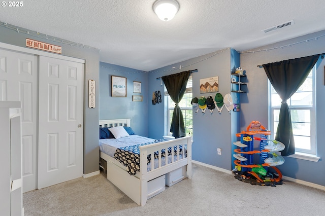 bedroom featuring carpet flooring, visible vents, and a textured ceiling