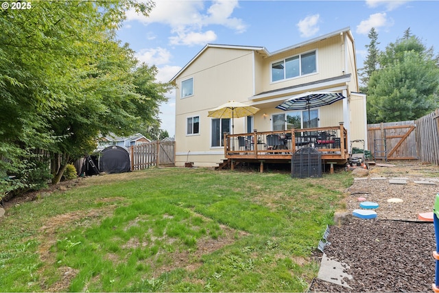 rear view of property with a deck, a lawn, a fenced backyard, and a gate