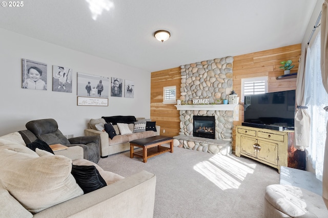 carpeted living room featuring wooden walls and a fireplace