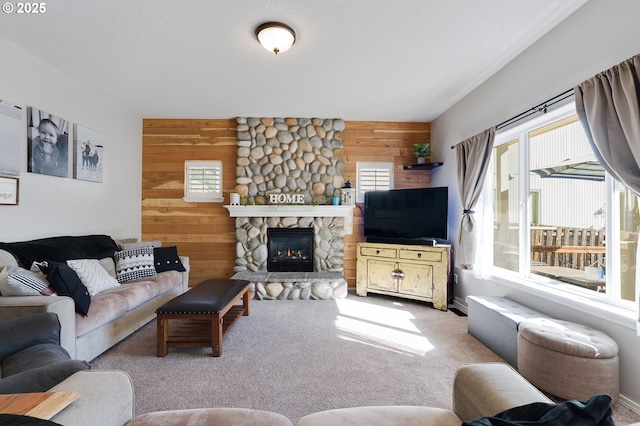 living area featuring a fireplace, wood walls, and carpet flooring