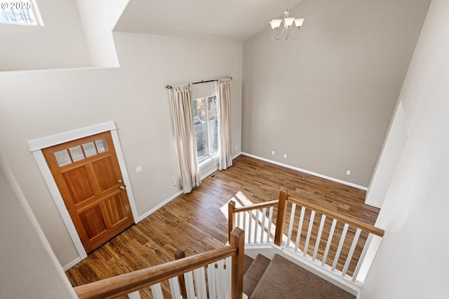 entryway with wood-type flooring, an inviting chandelier, and vaulted ceiling