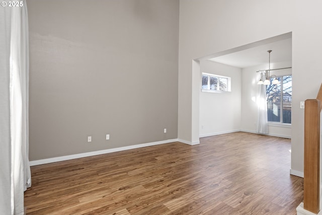 empty room featuring a chandelier and wood-type flooring