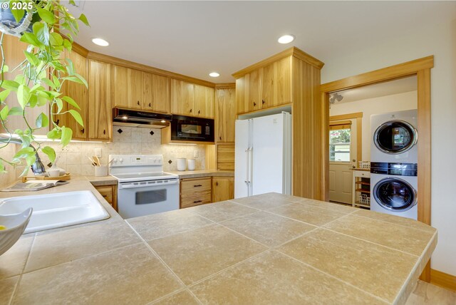 5818 SW Boundary St, Portland, OR 97221 - kitchen featuring white appliances, stacked washer / dryer, under cabinet range hood, decorative backsplash, and a sink