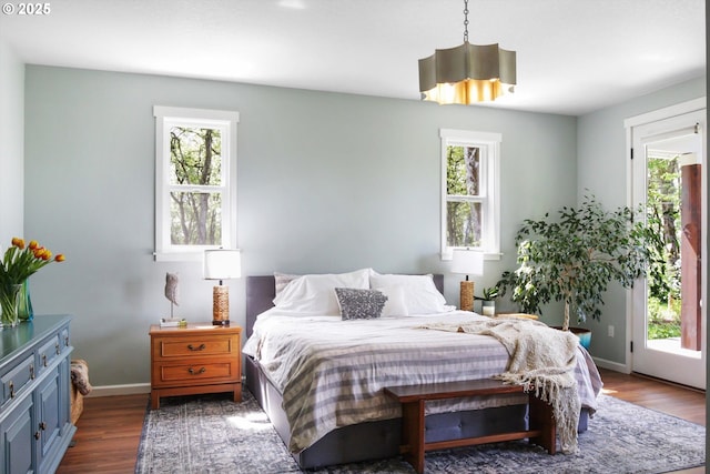 bedroom featuring baseboards, wood finished floors, and multiple windows