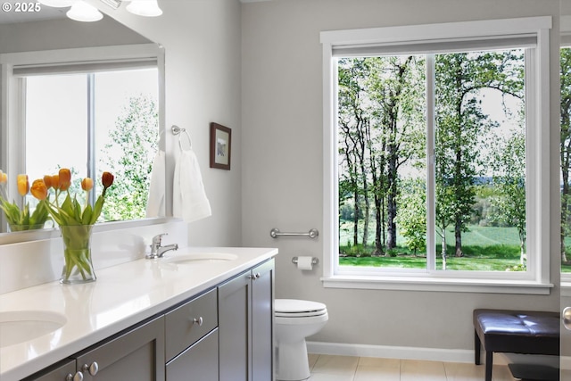 bathroom with a sink, baseboards, plenty of natural light, and toilet