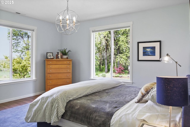 bedroom with an inviting chandelier, wood finished floors, and multiple windows