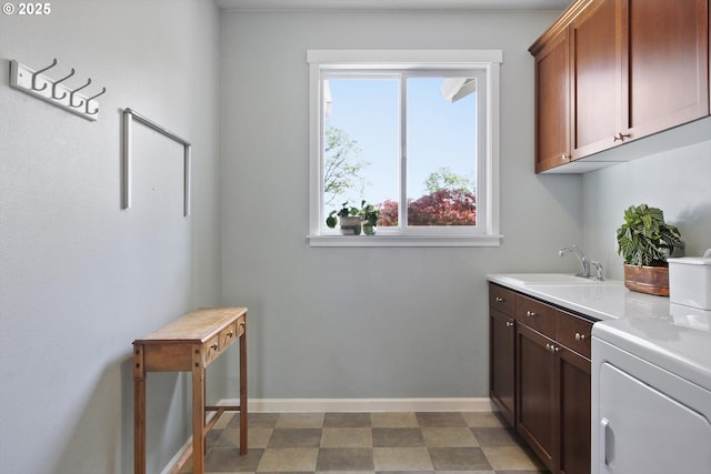 washroom featuring cabinet space, baseboards, a sink, and light floors