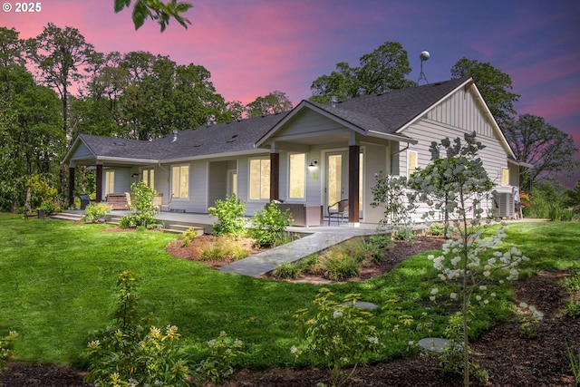 single story home with a lawn, a shingled roof, board and batten siding, and covered porch