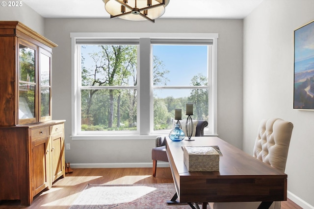 home office featuring a notable chandelier, wood finished floors, and a healthy amount of sunlight