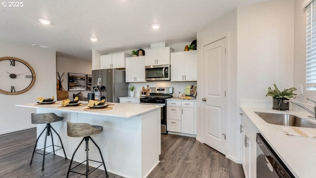 250 Greencrest St, Salem, OR 97301 - kitchen featuring appliances with stainless steel finishes, dark wood-style floors, a sink, a kitchen bar, and white cabinets