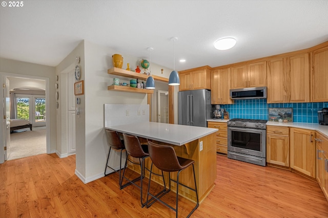 kitchen featuring light countertops, a peninsula, appliances with stainless steel finishes, and light wood-style floors