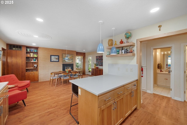 kitchen with a kitchen bar, open shelves, a fireplace, light wood-type flooring, and light countertops