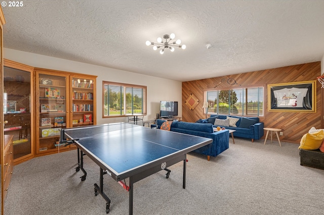 playroom with carpet floors, wood walls, and a textured ceiling