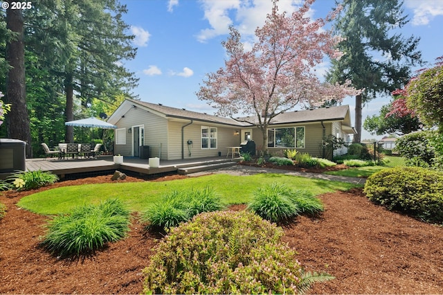 back of property with a yard, fence, and a wooden deck