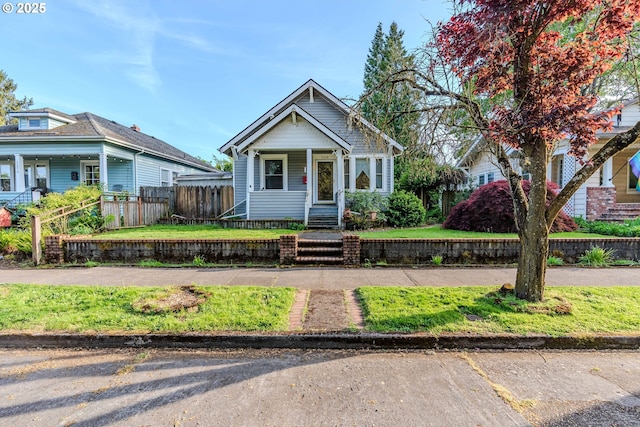 bungalow-style home with covered porch and fence