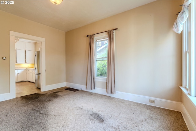 unfurnished room with baseboards and light carpet