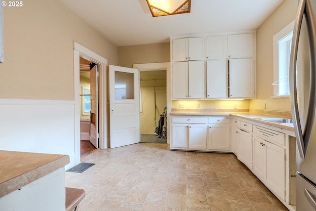 kitchen featuring a sink, light countertops, white cabinetry, and freestanding refrigerator
