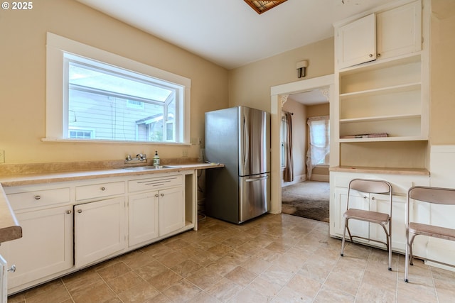 kitchen with freestanding refrigerator, a sink, a healthy amount of sunlight, and light countertops