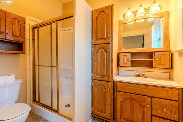 bathroom featuring toilet, a shower stall, and vanity