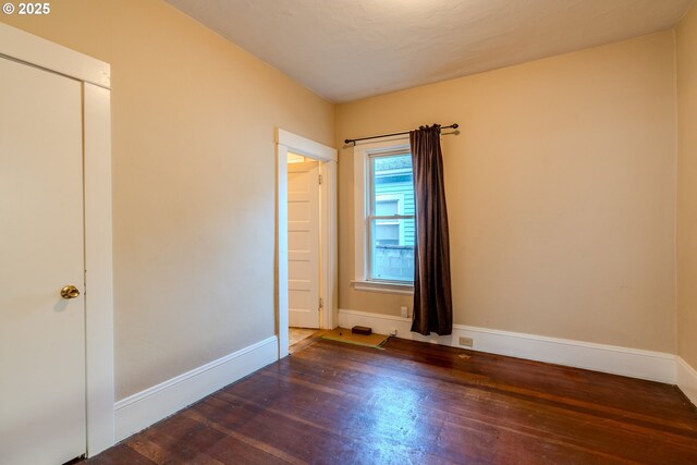 unfurnished room with baseboards and wood finished floors