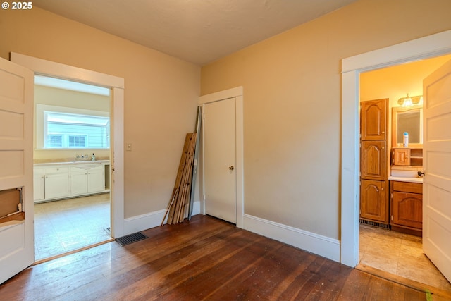 empty room featuring a sink, baseboards, and hardwood / wood-style flooring