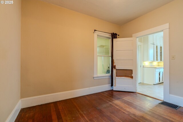unfurnished room with baseboards, hardwood / wood-style floors, and visible vents
