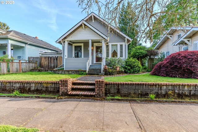 view of front of house with fence, covered porch, and a front yard