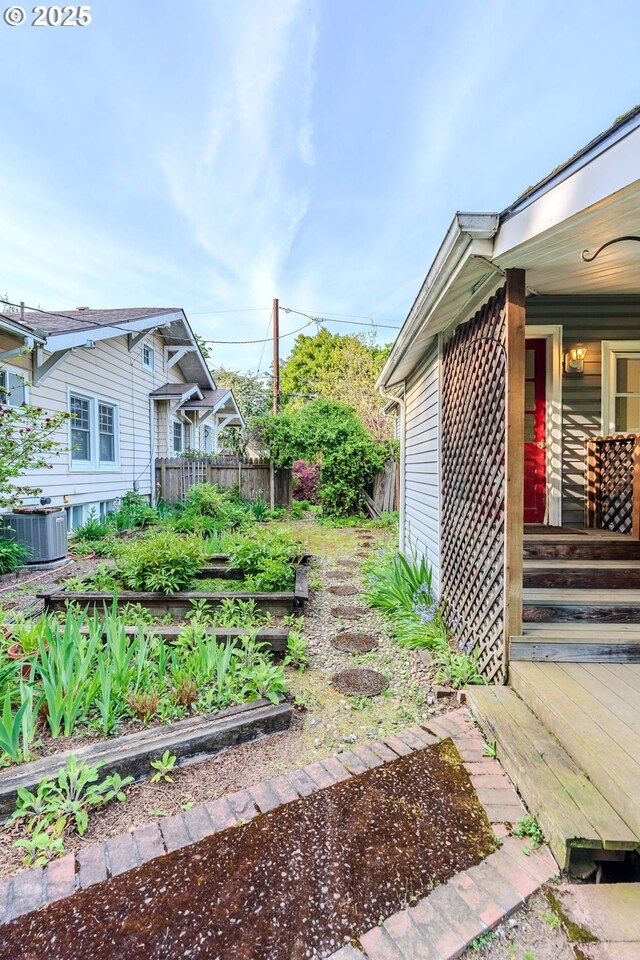 view of yard featuring central air condition unit, covered porch, a vegetable garden, and fence