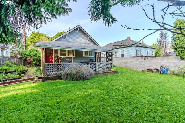 back of house featuring fence, covered porch, and a yard