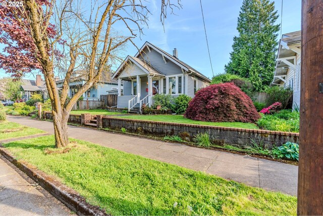 bungalow-style home featuring fence, a chimney, and a front lawn