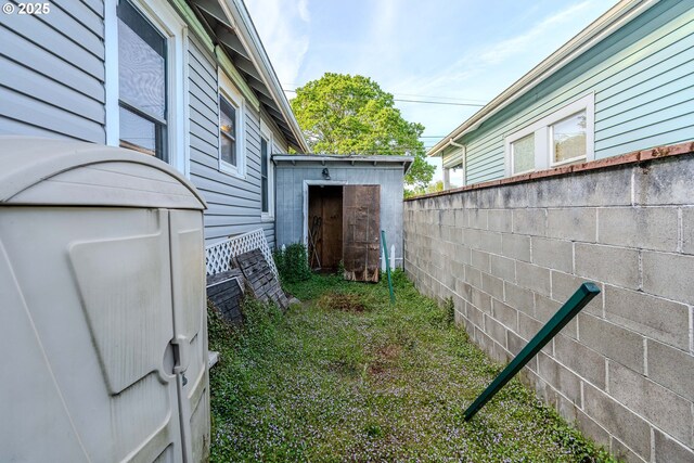 view of side of home with an outbuilding, fence, and a storage shed