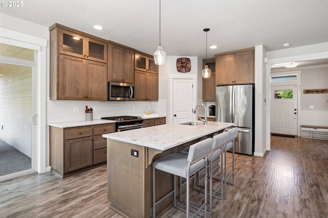12209 Mimosa Way, Oregon City, OR 97045 - kitchen with appliances with stainless steel finishes, a sink, wood finished floors, a kitchen bar, and an island with sink