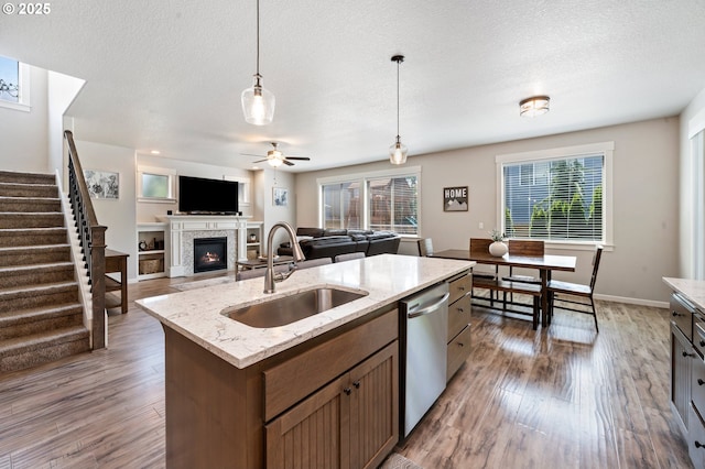 12209 Mimosa Way, Oregon City, OR 97045 - kitchen with dishwasher, a sink, a glass covered fireplace, healthy amount of natural light, and a textured ceiling