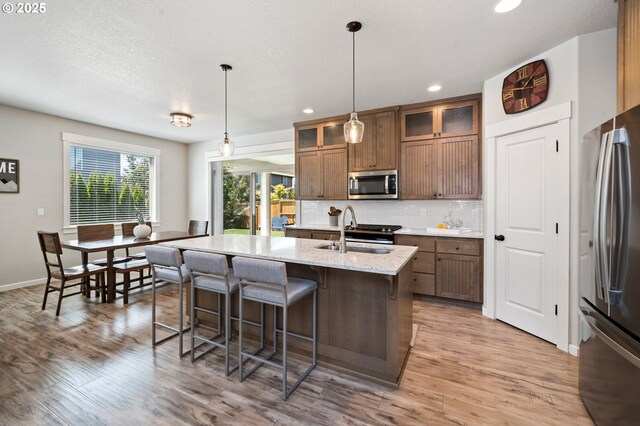 12209 Mimosa Way, Oregon City, OR 97045 - kitchen with stainless steel appliances, a sink, a kitchen bar, light wood-style floors, and recessed lighting